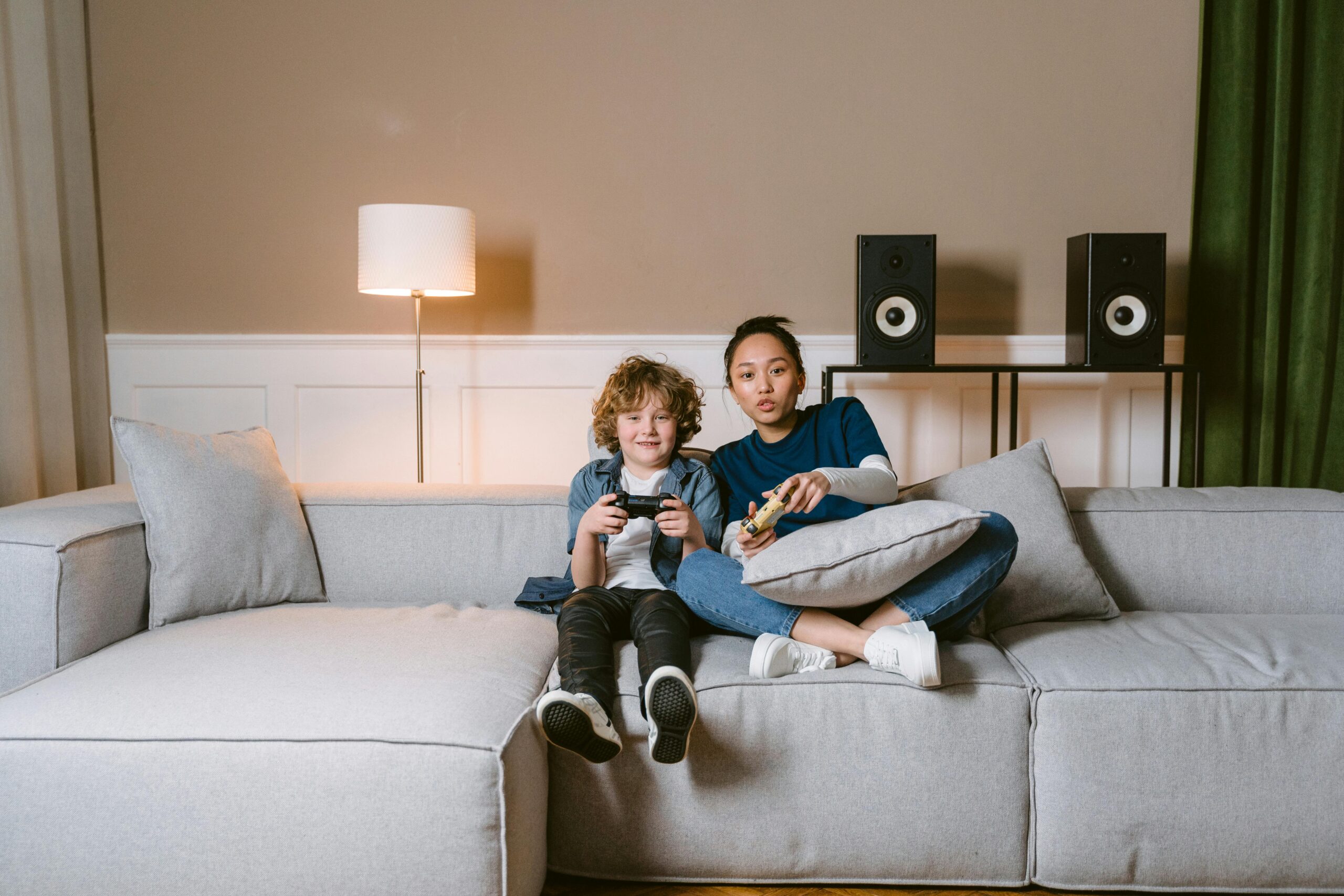 A woman and child sitting on a couch, engaged in playing video games together.