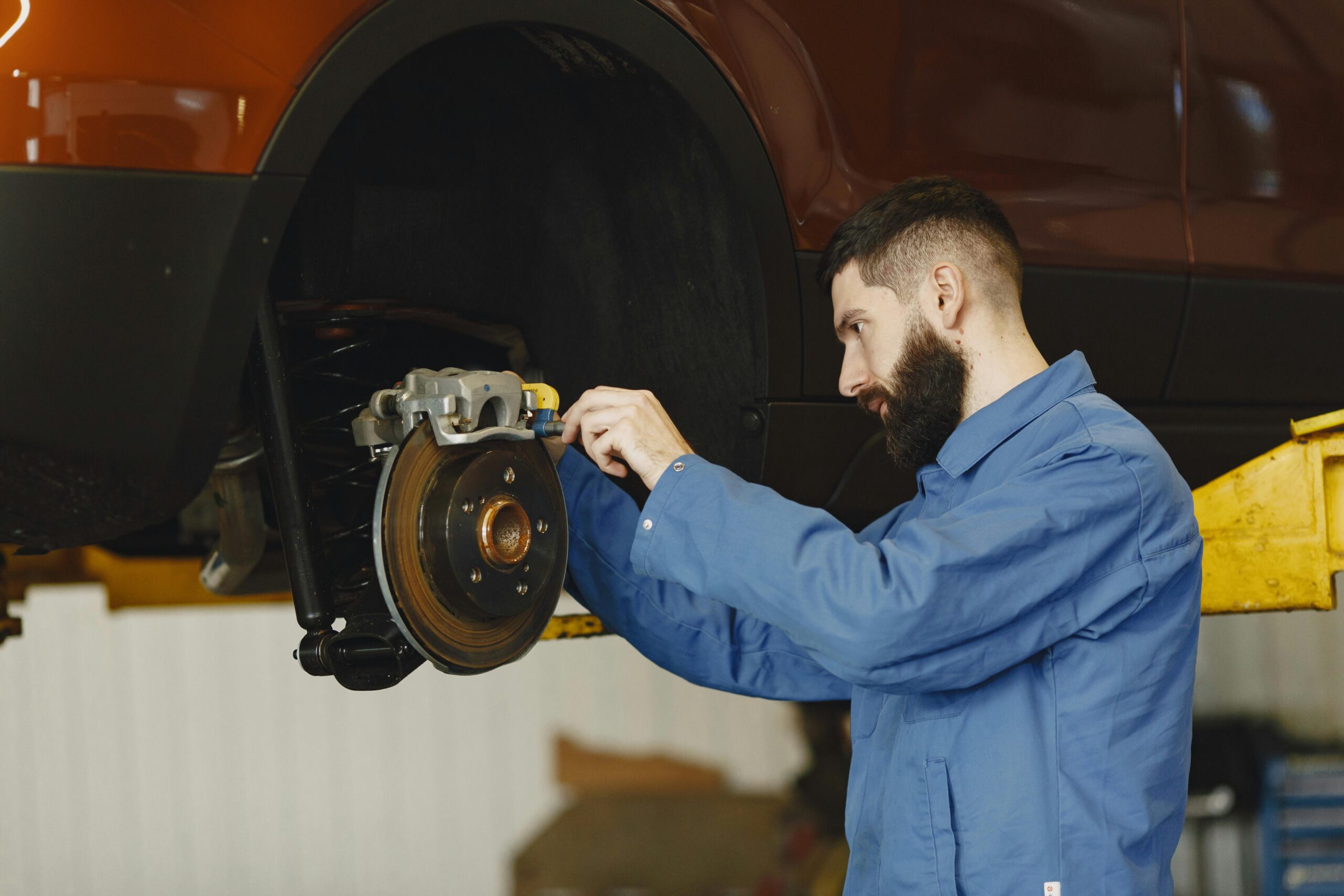 A man is focused on repairing a car's brake system, demonstrating his mechanical skills and attention to detail.