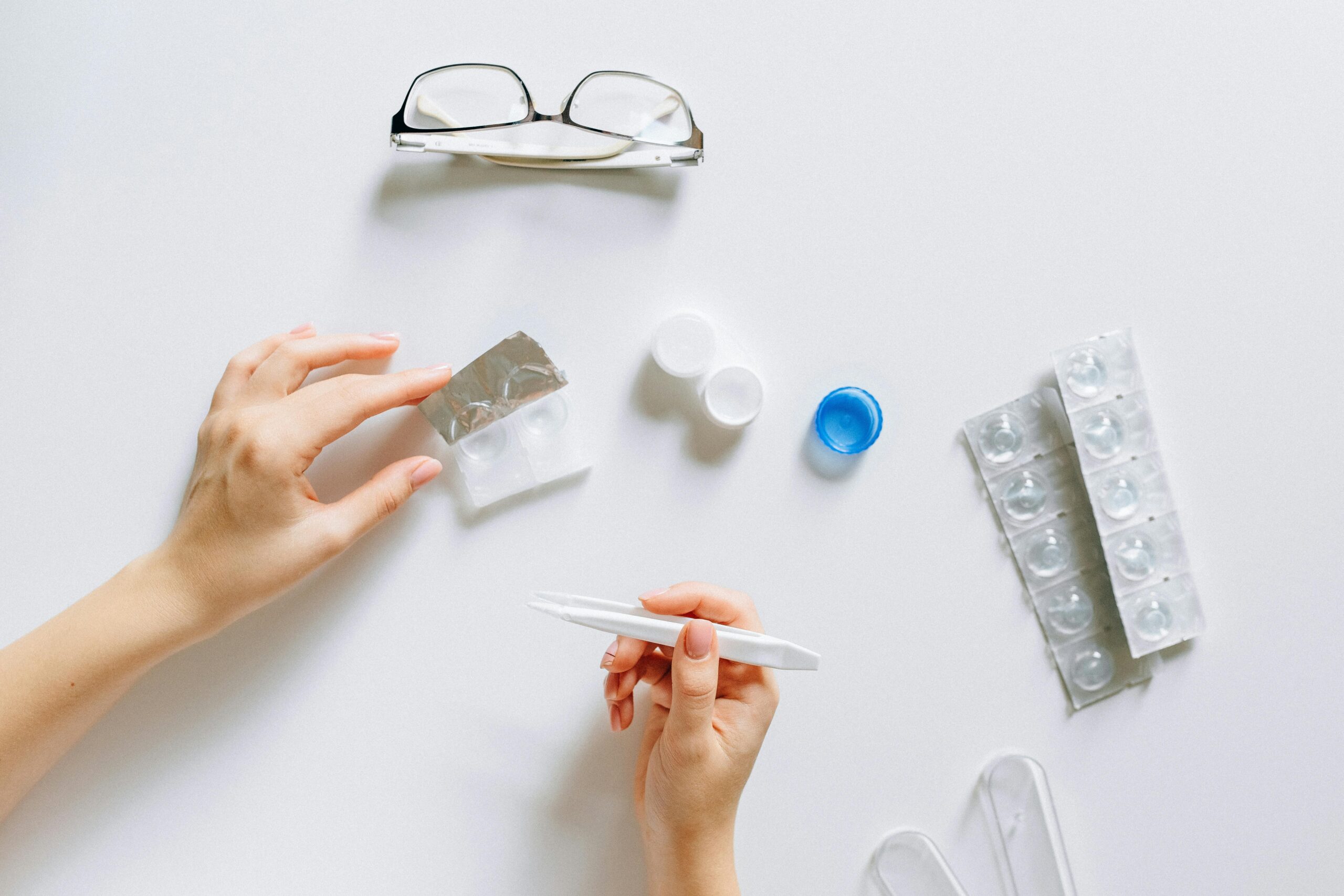 A woman's hands holding a pair of glasses alongside various other items, showcasing a casual and organized arrangement.