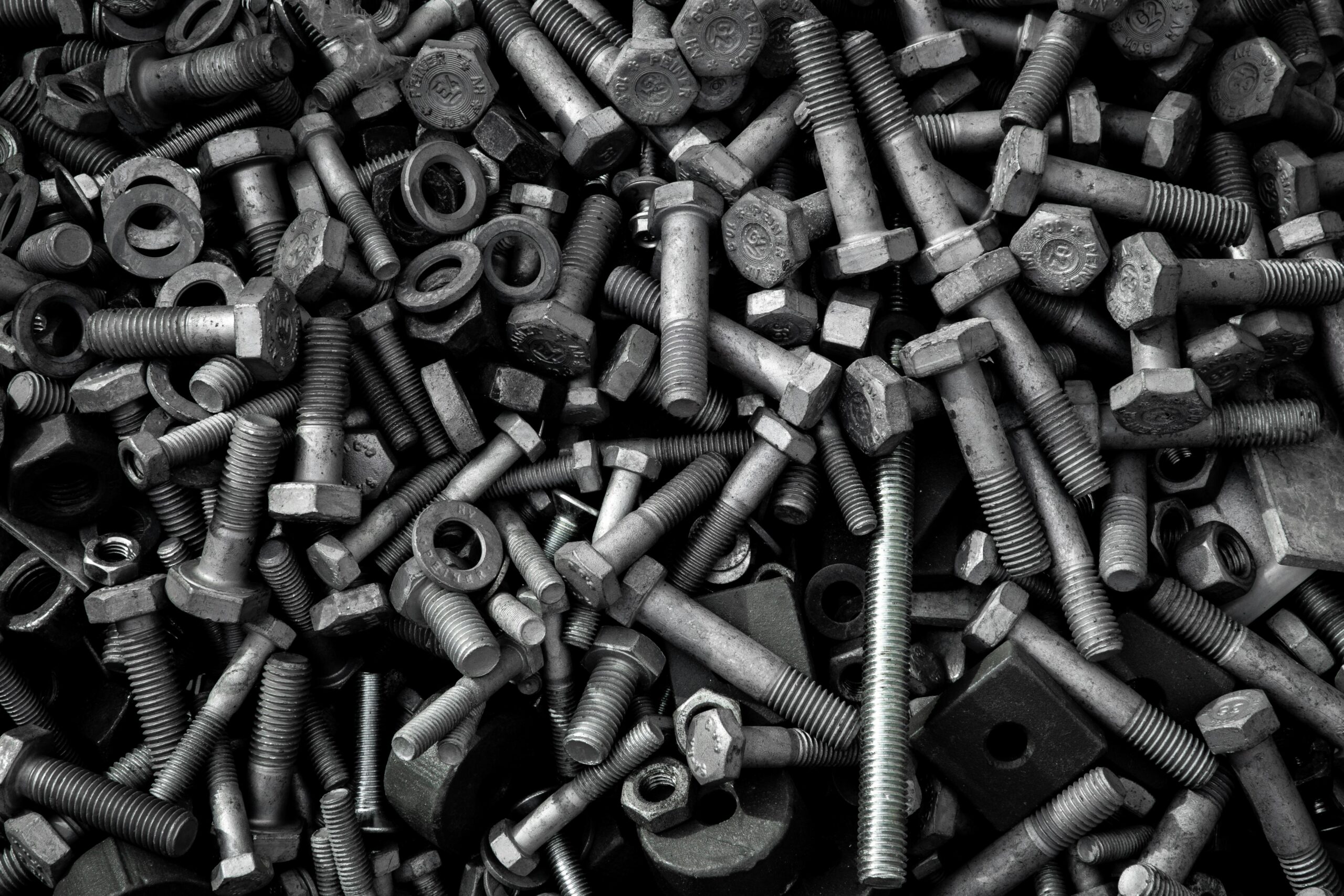 A close-up view of a pile of assorted metal screws and nuts, showcasing their varied sizes and shapes.