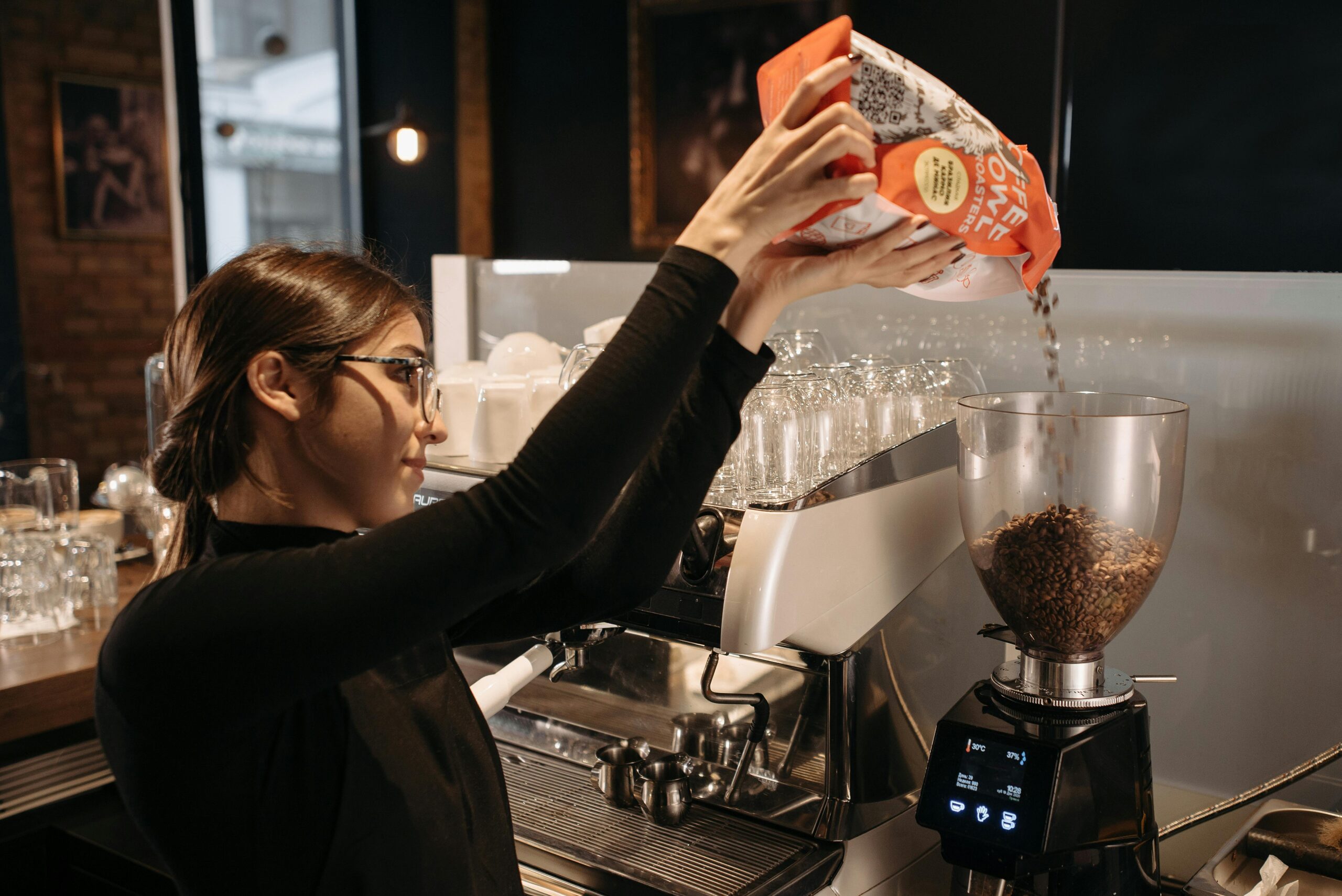 A woman pouring coffee into a coffee machine, preparing to brew a fresh pot of coffee in a cozy kitchen setting.