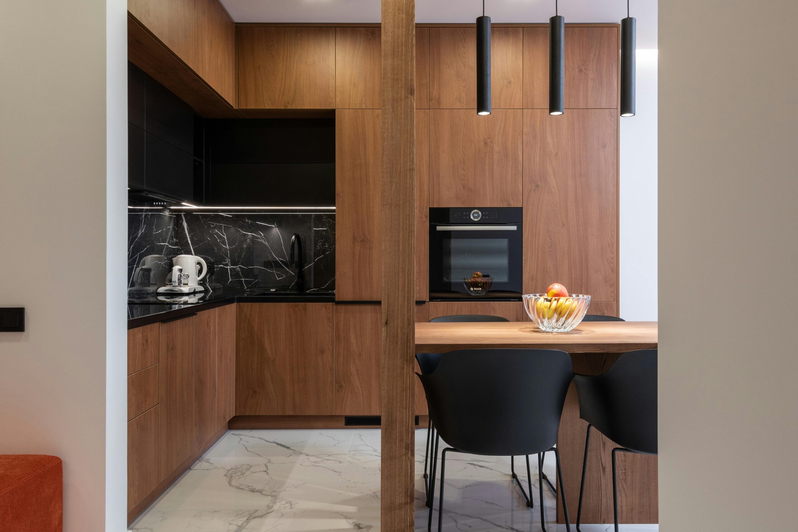 A modern kitchen featuring a wooden island and elegant black marble countertops, showcasing a stylish and functional design.