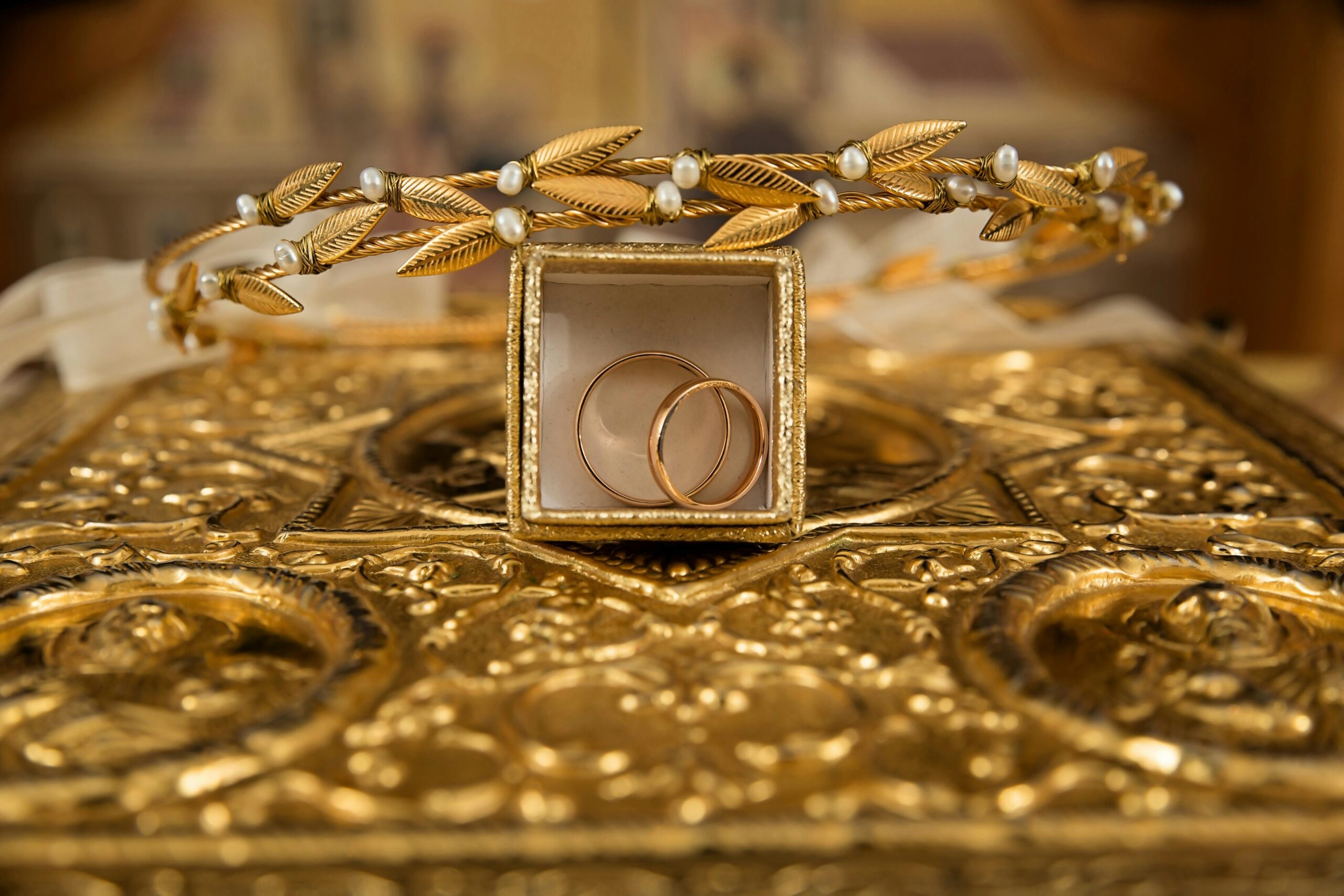 Gold wedding rings nestled in a box on a table, representing the union of two individuals in marriage.