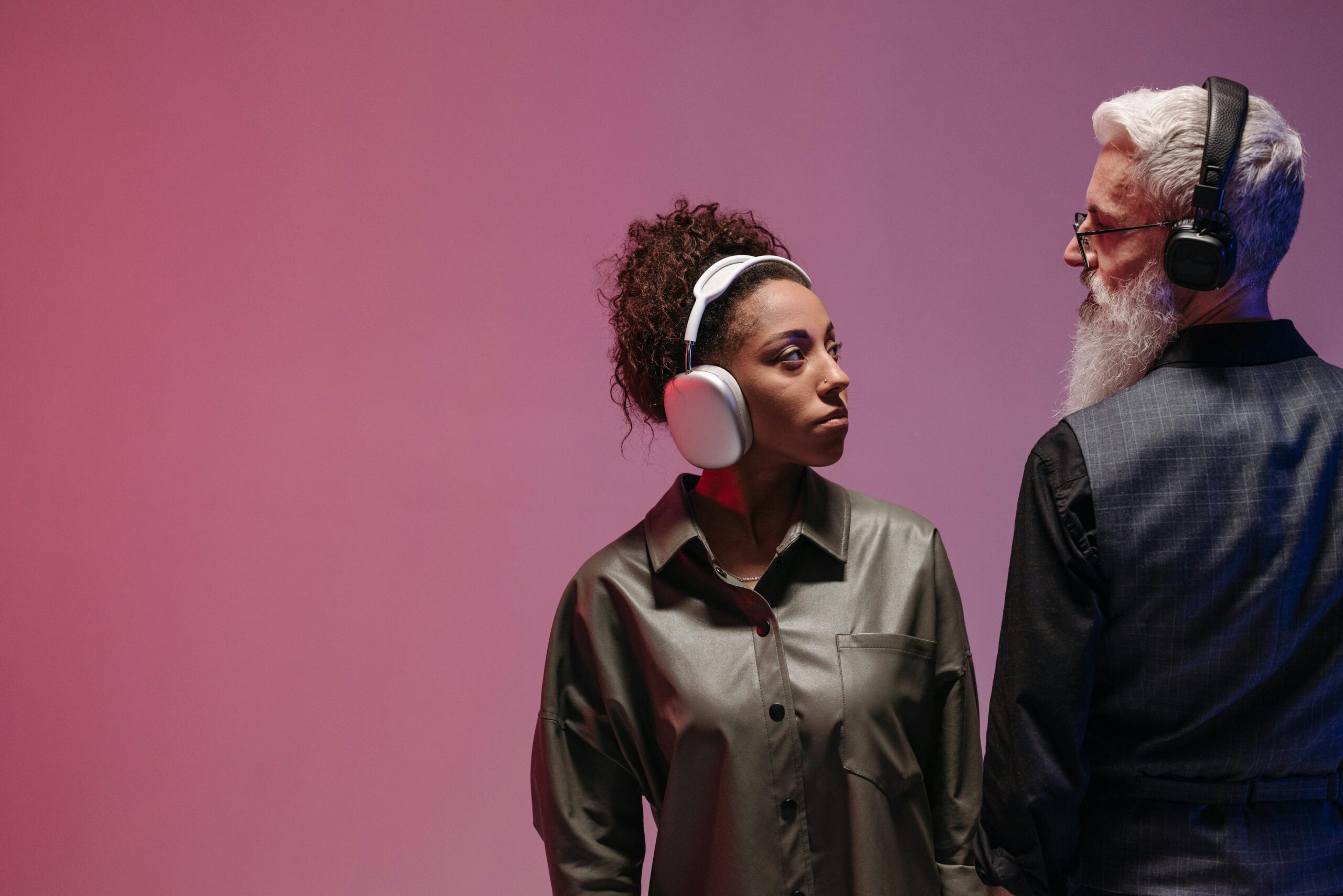 A man and woman wearing headphones, engaged in conversation, with a relaxed atmosphere in a modern setting.