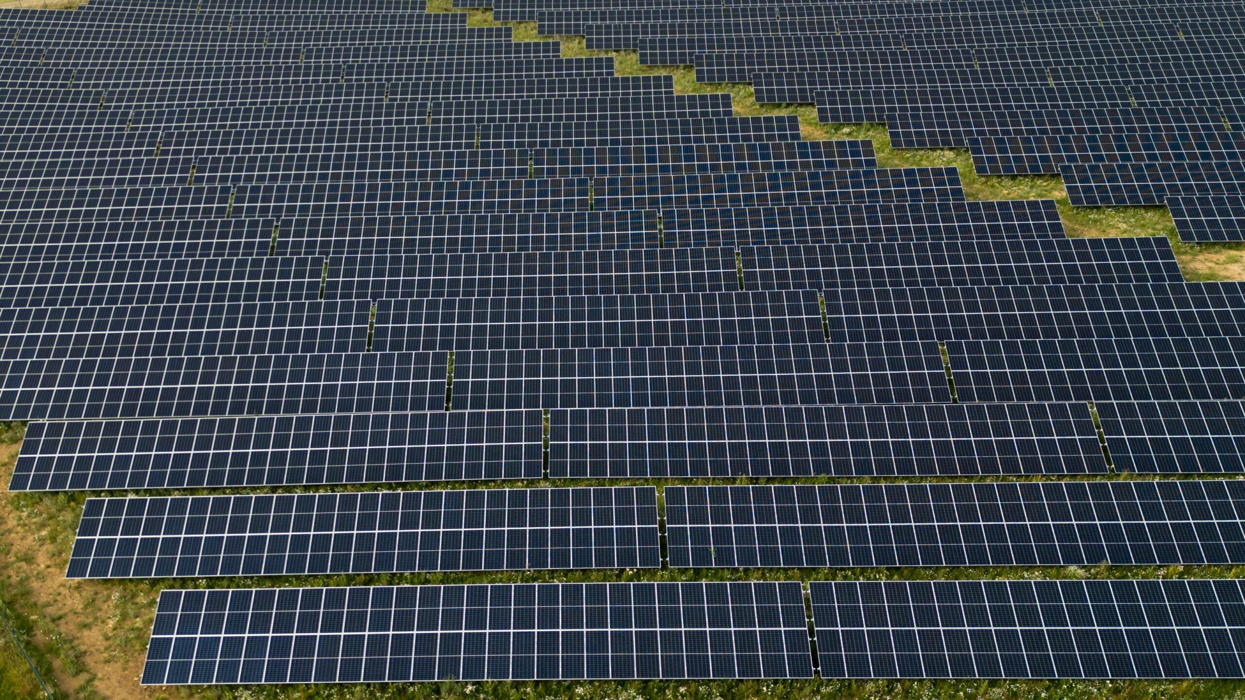 Aerial view showcasing numerous rows of solar panels arranged in a grid pattern across a landscape.