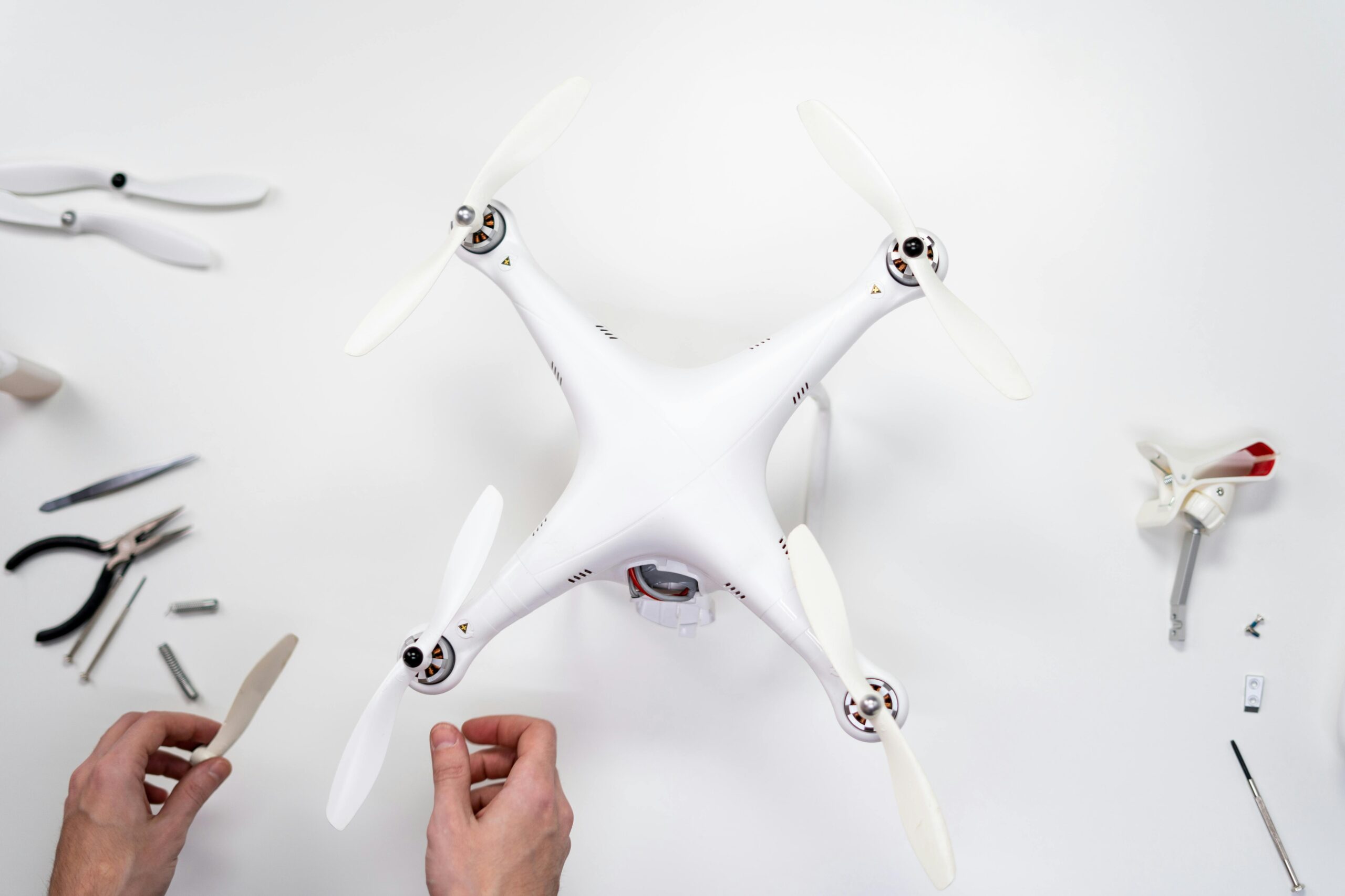 A person is assembling a white drone, focused on the intricate components and controls.