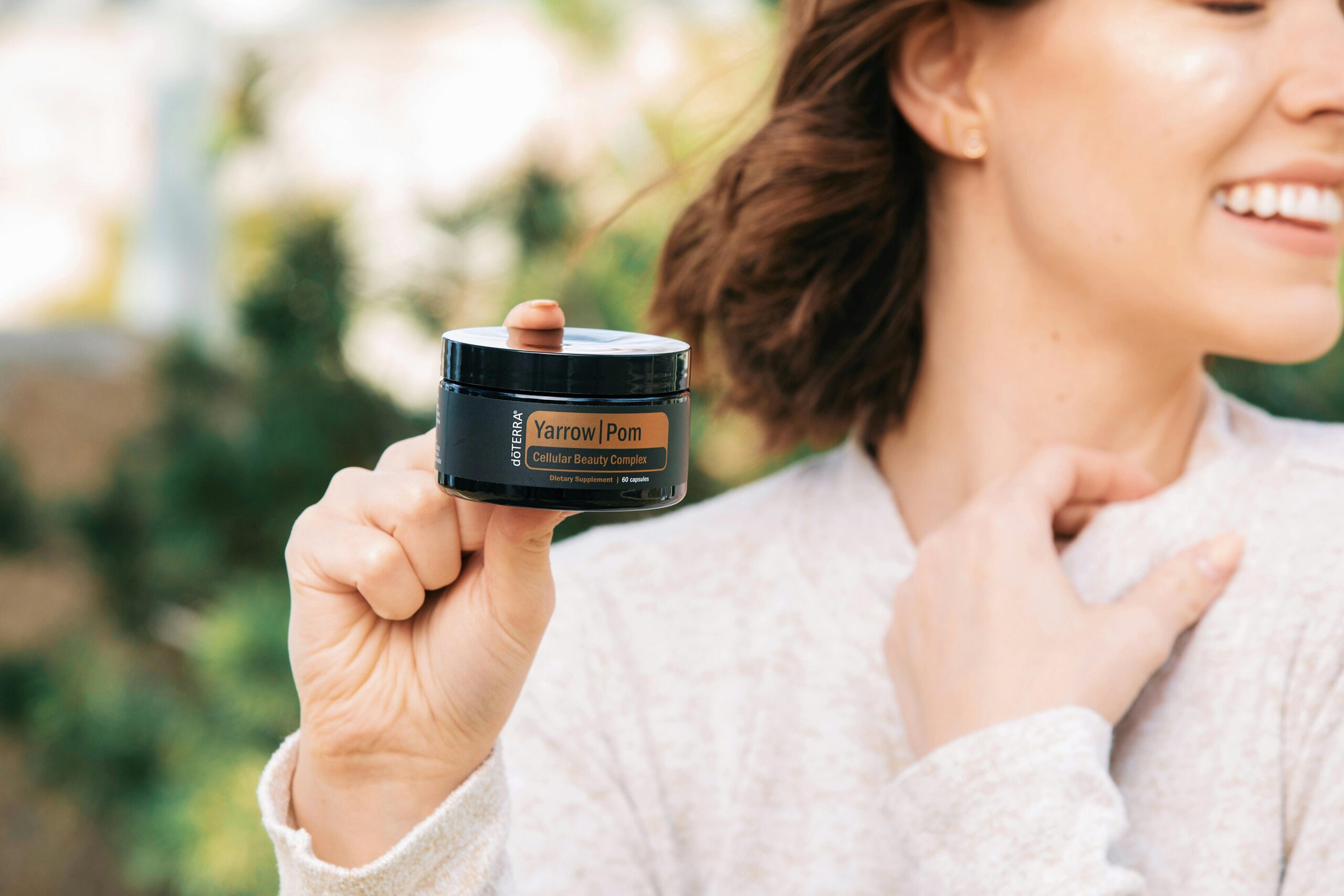 A woman displays a jar of black face cream, emphasizing its distinctive appearance and the elegance of the product.